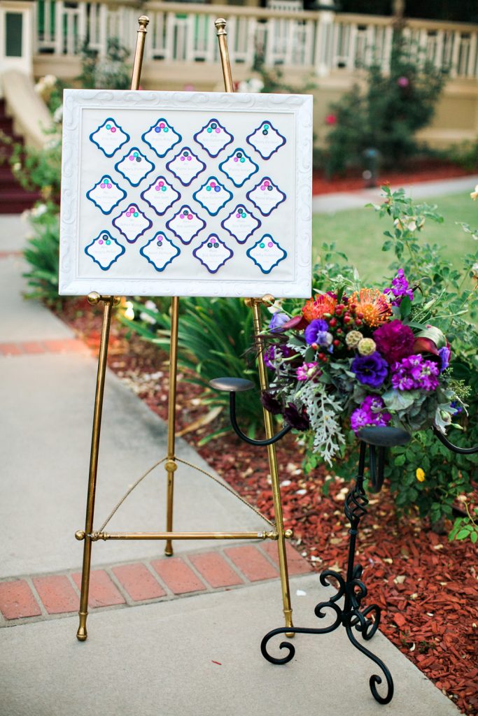 Wedding escort cards framed on easel buttons in jewel tone