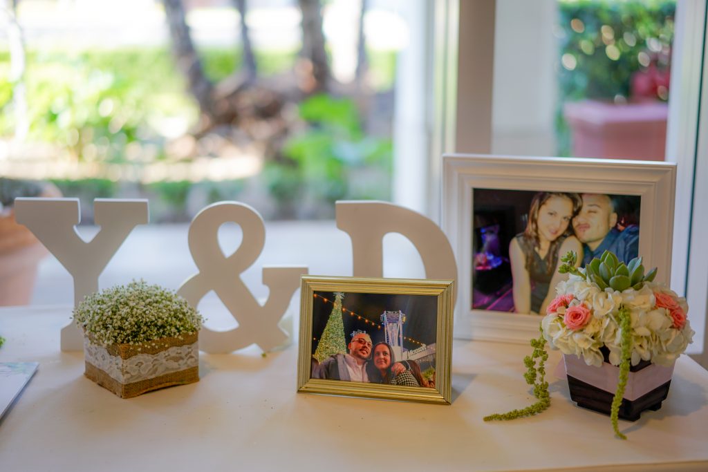 Guestbook table decor with wooden letter initials, framed photos, and small floral arrangements.