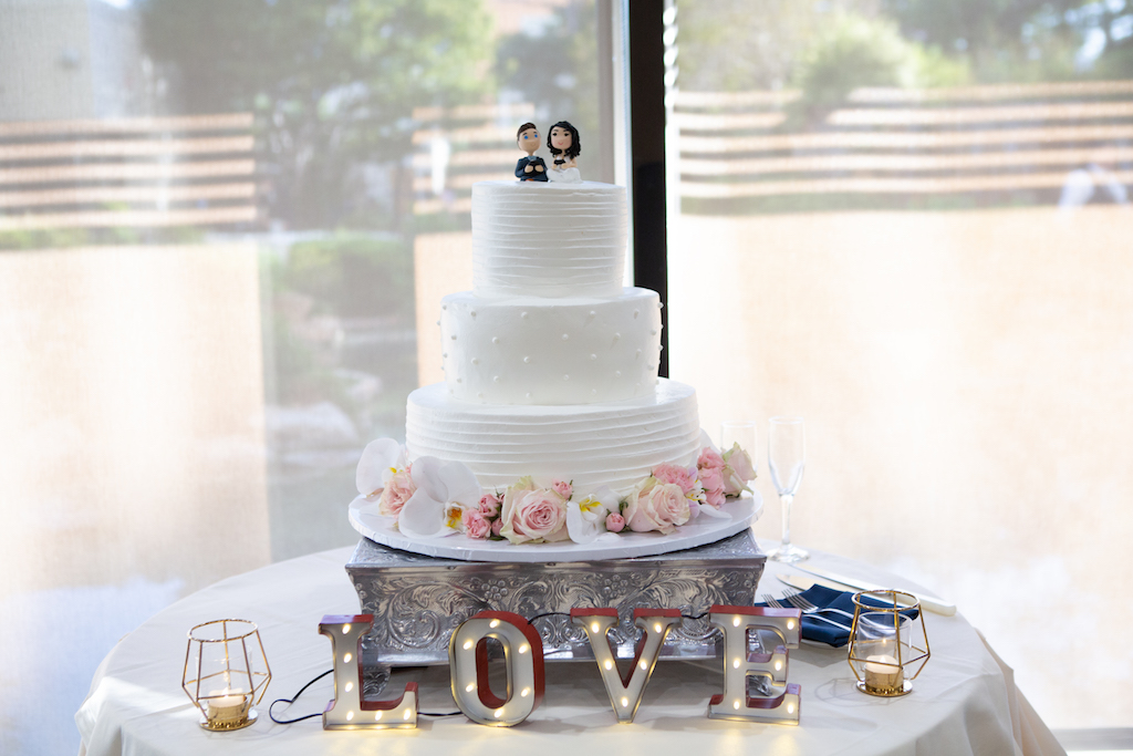A custom three-tiered wedding cake from King's Hawaiian Bakery, adorned with fresh flowers and a custom cake topper.

Edwin So Photography