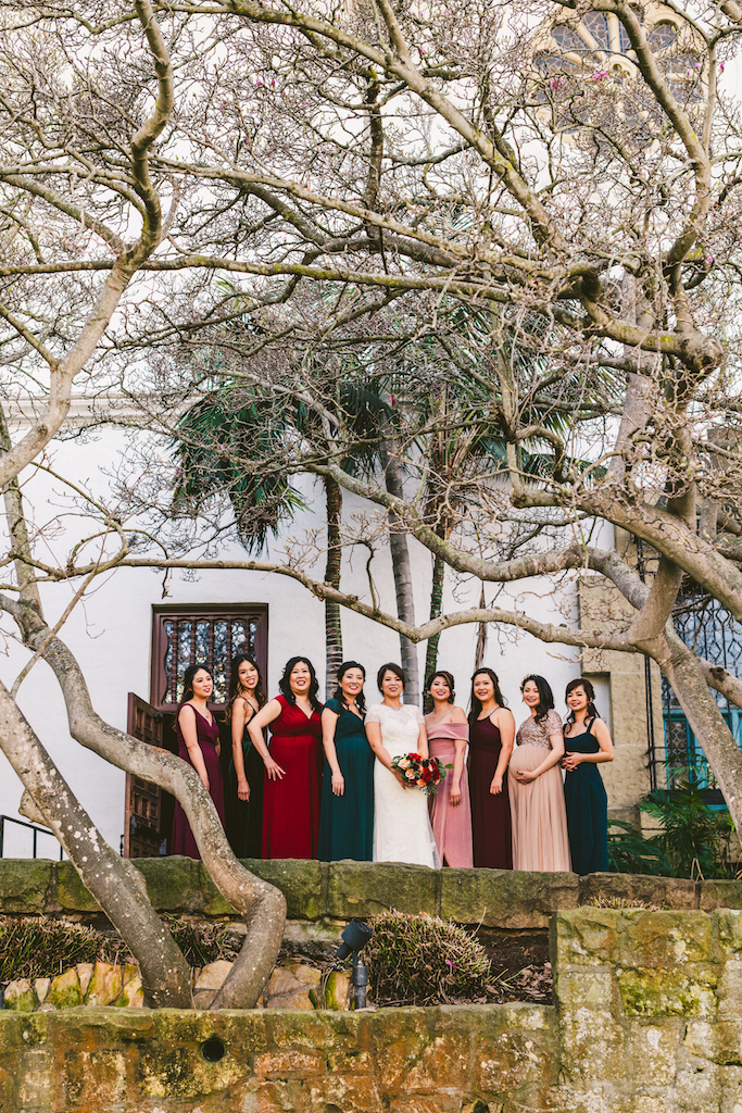 The bridal party wore dresses in shades of red, blush, and green for a romantic color palette.