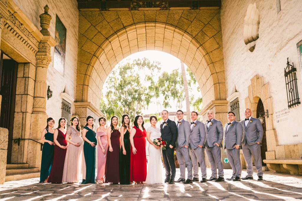 The bridal party wore dresses in shades of red, blush, and green for a romantic color palette.